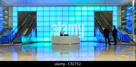 Bunte blaues Licht an der Wand hinter der Rezeption im Eingangsbereich zu Bürogebäude innen Fahrtreppen Stockwerke über der Stadt London England Großbritannien Stockfoto