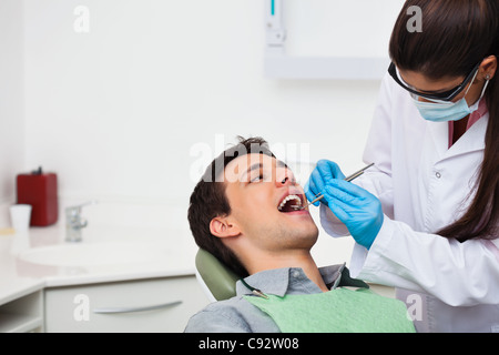 Zahnärztin, die einem männlichen Patienten in Klinik Stockfoto