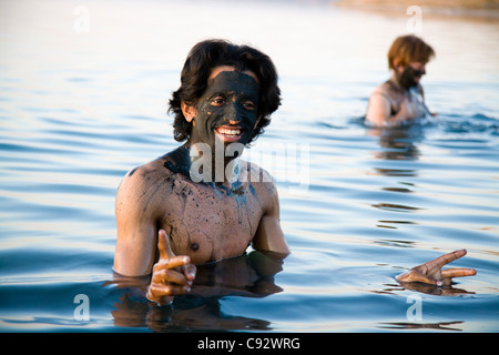 Mann / Mann / Männer / Tourist / Touristen mit Schlamm Gesicht pack in hohen Salz Inhalte / salzig salzhaltigem Wasser des jordanischen Totes-Meer-See. Stockfoto