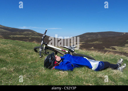 Eine junge Frau, die Entspannung durch ihr Mountainbike auf der Überfahrt von Skiddaw im Lake District Stockfoto