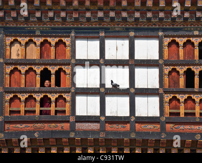 Ein junger Novize schaut die beeindruckende Dzong oder Festung am Trashigang aus einem shuttered Fenster. Stockfoto