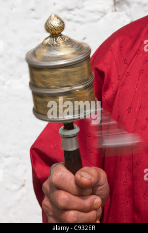 Eine buddhistische Frau spinnt ihr Handheld Gebetsmühle im Uhrzeigersinn. Stockfoto