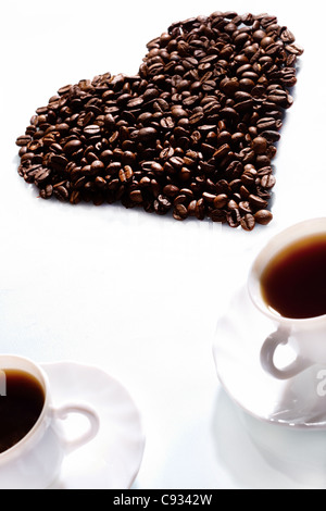 Bild der Kaffeebohnen in Form von Herzen mit zwei Tassen Espresso in der Nähe von Stockfoto