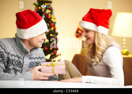 Porträt von überrascht Frau betrachten Geschenkbox in ihrem Mann die Hände am Weihnachtstag Stockfoto