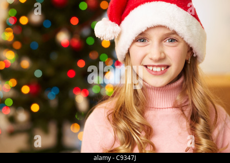 Entzückende Mädchen in Nikolausmütze Blick in die Kamera Lächeln Stockfoto