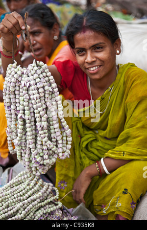 Eine Frau verkauft Girlanden der Blumen in der geschäftigen Mullik Ghat Blumenmarkt in der Nähe von Howrah Brücke. Stockfoto