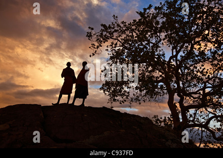 Zwei Maasai-Männer auf einem Hügel bei Sonnenuntergang Silhouette. Stockfoto