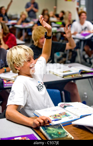 Eine Blondine hält begeisterten acht Grade junge seine Hand eine Frage in der Klasse an einer Mittelschule in Südkalifornien. Stockfoto