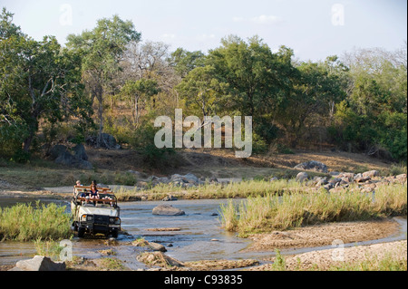 Malawi, Majete Wildlife Reserve.  Familie auf Safari überqueren Sie den Mkulumadzi Fluss in ihrem Safari-Fahrzeug. Stockfoto