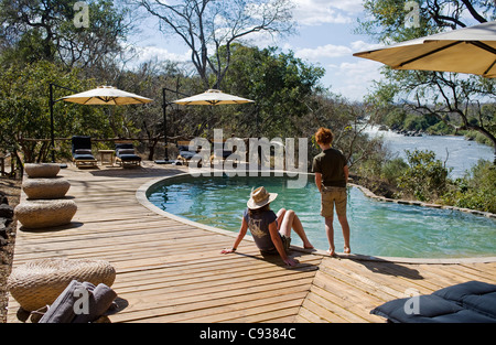 Malawi, Majete Wildlife Reserve.  Zwei Besucher auf einer Safari entspannen Sie am Swimmingpool. HERR Stockfoto