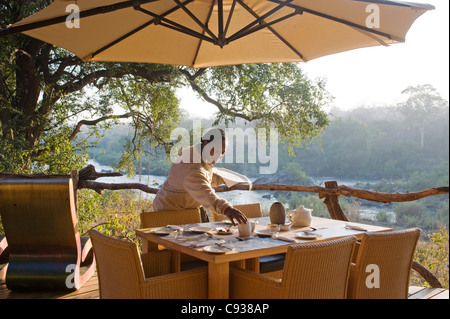 Malawi, Majete Wildlife Reserve.  Eine Kellnerin setzt den Frühstückstisch in Mkulumadzi lodge Stockfoto