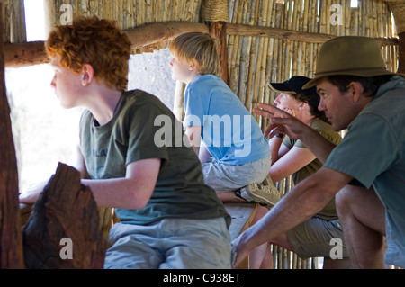 Malawi, Majete Wildlife Reserve.  Safari-Guide weist darauf hin Tierwelt aus einem Versteck in Majete, eine Familie auf Safari. Stockfoto