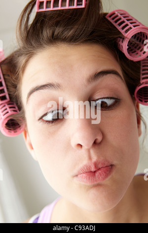 Teenager-Mädchen mit Haar in Lockenwicklern zieht ein Gesicht Stockfoto