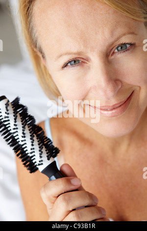 Mitte Alter Frau mit Haarbürste Stockfoto