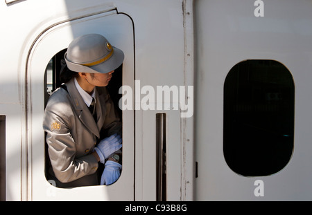 Eine Wärterin schaut ihre Uhr aus dem Fenster eines shinkansen (Schnellzug) der Klasse JR 700 am Bahnhof Shin-Yokohama, Yokohama, Japan Stockfoto