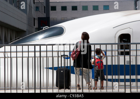 Eine Mutter und ein Sohn beobachten einen shinkansen (Schnellzug) der Klasse JR 700 am Bahnhof Shin-Yokohama in Yokohama, Japan. Stockfoto