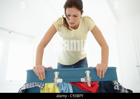 Frau, die kämpfen, um Koffer zu schließen Stockfoto