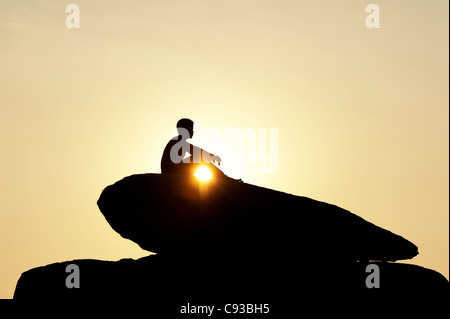 Indischer Mann saß auf einem Felsen bei Sonnenuntergang Stockfoto