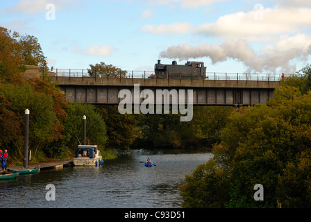 Restaurierte Dampflok Fluß Avon in der Nähe von gebissen über eine ursprüngliche sobald stillgelegte Brücke überqueren, während eine Kanu unter geht Stockfoto