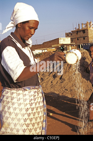 Meru Frau Reis gießen seine Qualität bei Duka mit Reis für Verkauf Meru Bezirk Markt Kenia zeigen Stockfoto