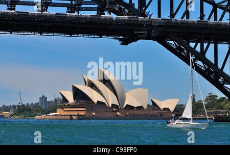 Blick auf das Wasser von der Fähre auf das berühmte Opernhaus von Sydney mit einer Segelyacht, die unter der Sydney Harbour Bridge, Australien, segelt Stockfoto