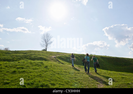 Drei junge Menschen zu einen grasbewachsenen Hügel klettern Stockfoto