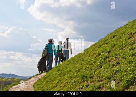 Drei junge Menschen zu einen grasbewachsenen Hügel klettern Stockfoto