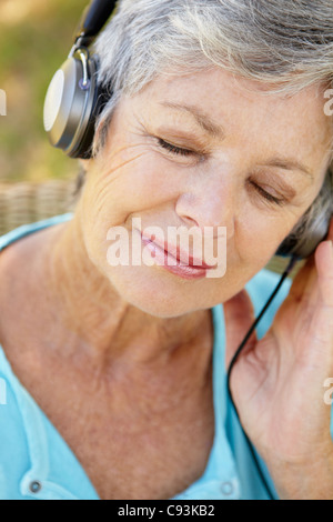 Ältere Frau anhören von Musik im freien Stockfoto