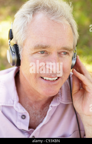 Senior woman anhören von Musik im freien Stockfoto