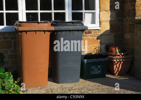 Wheelie-Behälter, Braun für Gartenabfälle und schwarz für Hausmüll und eine Box für Wertstoffe. Stockfoto