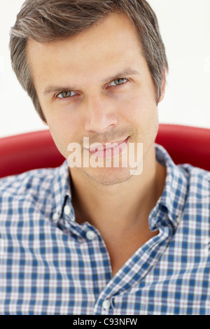 Mann sitzt im roten Stuhl Stockfoto