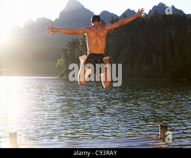 Junger Mann in See springen Stockfoto