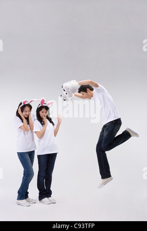 Zwei Frauen in Rabbit Kostüm mit Mann in Tiger Kostüm stehen im Studio, Porträt Stockfoto