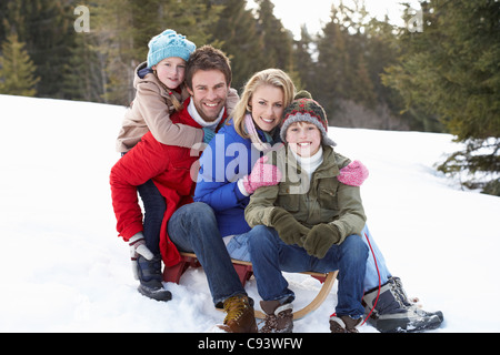Junge Familie sitzt auf einem Schlitten im Schnee Stockfoto