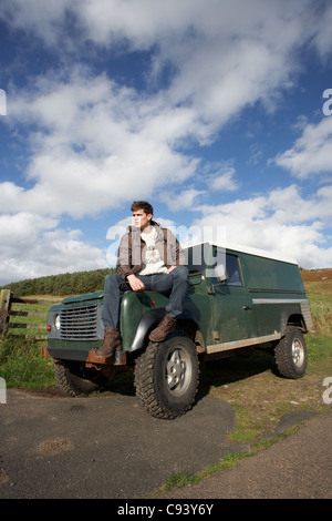 Junger Mann in der Landschaft mit SUV Stockfoto