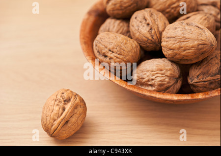 Schale Walnüsse auf einer hölzernen Oberfläche mit einer einzigen Nussbaum im Vordergrund Stockfoto