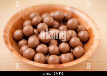 Detail einer Holzschale mit leckere Vollmilchschokolade Kugeln auf einer Holzoberfläche Stockfoto