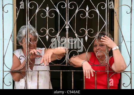 Zwei kubanische Frauen hinter dem traditionellen vergitterten Fenster in Trinidad, Kuba. Stockfoto