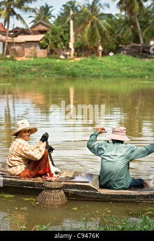 Ein Mann und eine Frau auf einem Boot versuchen, Fischfang mit Netzen, auf die Siem-Reap-Fluss in Kambodscha, während der Regenzeit Stockfoto