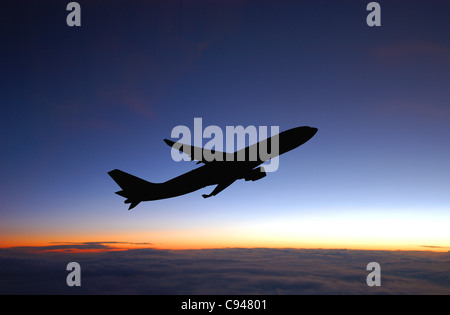 Passagierflugzeug während Flug und blauer Himmel nach Sonnenuntergang. Stockfoto