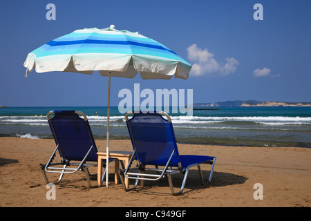 Liegestühle am Strand von Agios Stephanos, in der Nähe von Sidari, Korfu, Griechenland im Hinblick auf die Nisos Mathraki und Nisos Ereikoussa Inseln Stockfoto