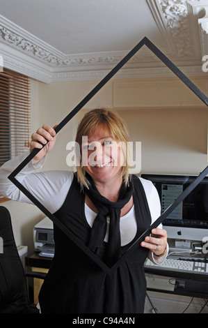 Frau arbeitet im Büro durch leeren Grafikrahmen lächelnd fotografiert November 2011 Stockfoto