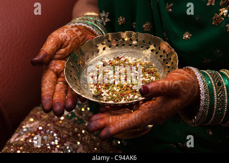 Indien, Assam, Guwahati, traditionellen Mehndi Henna dekorative Muster auf den Händen der Braut Holding Schüssel mit sof Stockfoto