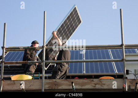 Handwerker Einbau von neuen Solarmodulen zu einem Wohnhaus Dach für die Einspeisevergütung. Wales, Großbritannien, Großbritannien Stockfoto