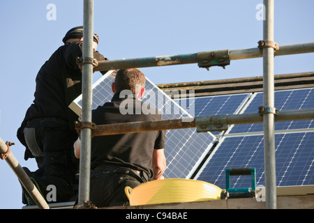 Handwerker Installieren von neuen Solarmodulen zu einem Haus Dach für die Einspeisevergütung. Wales, Großbritannien, Großbritannien Stockfoto