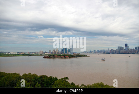 Blick auf die Südseite des Ellis Island mit Hintergrund von Jersey City, NJ, Hudson River und lower Manhattan auf der rechten Seite. Stockfoto