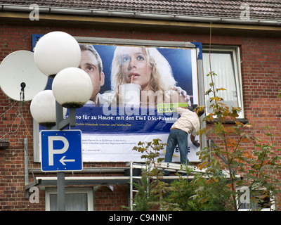 Billsticker arbeiten auf ein Plakat für ein Haus in Winsen-Luhe, Niedersachsen, Deutschland. Stockfoto