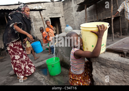 Einwohner von Temeke, einem Slum in Dar Es Salaam, Tansania, Ostafrika, sammeln Wasser aus einem Hahn der Gemeinschaft. Stockfoto