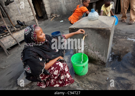 Einwohner von Temeke, einem Slum in Dar Es Salaam, Tansania, Ostafrika, sammeln Wasser aus einem Hahn der Gemeinschaft. Stockfoto