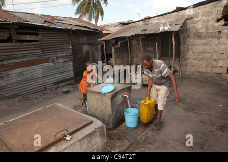 Einwohner von Temeke, einem Slum in Dar Es Salaam, Tansania, Ostafrika, sammeln Wasser aus einem Hahn der Gemeinschaft. Stockfoto